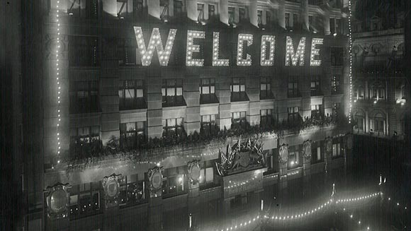 Photograph showing how the Commonwealth Bank appeared by night during the visit.  Both direct and flood lighting were used, the building as a whole being one of the most attractively dressed in the city.  Sir Denison Miller acted as Chairman of the Martin Place and Moore Street Committee.