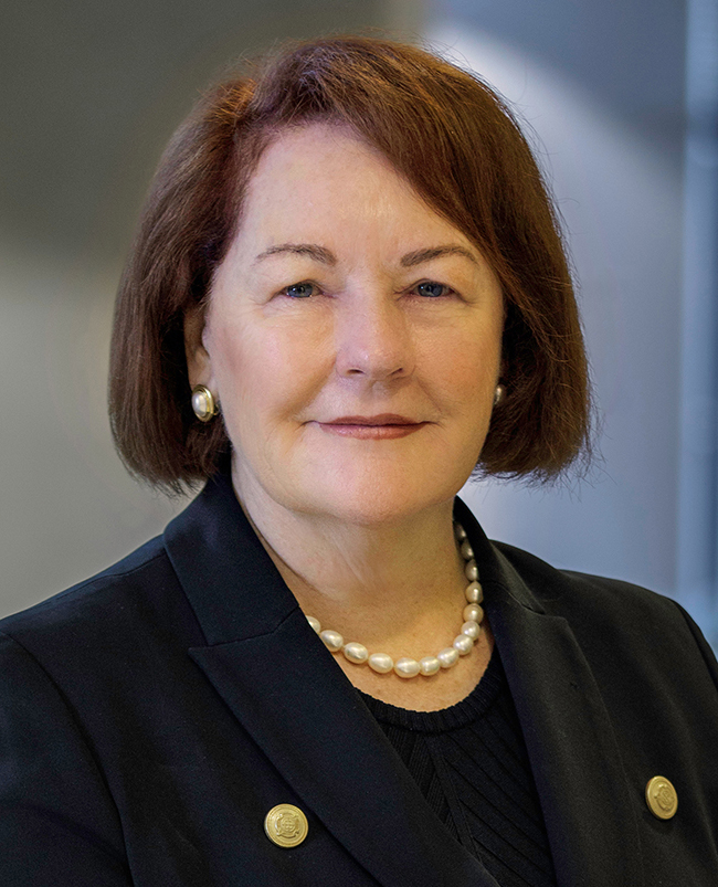 A headshot photograph of Deborah, looking directly at the camera and smiling. 